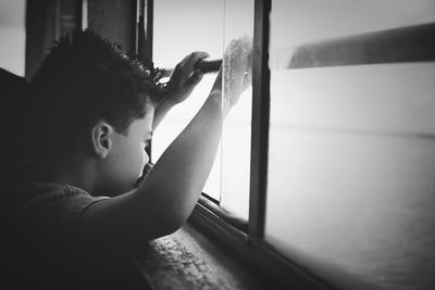 Side view of boy looking through ferry window