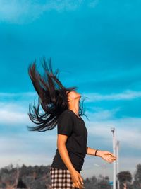 Full length of young woman standing against sky