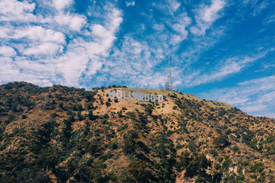 Low angle view of text on hill against sky