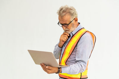 Midsection of man holding eyeglasses against white background