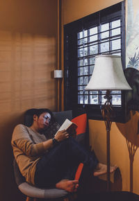 Young man using mobile phone while sitting on sofa at home