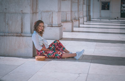 Portrait of woman sitting by column on floor