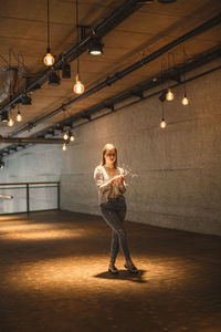 Portrait of young woman holding illuminated string lights