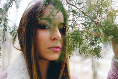 Close-up portrait of girl sen through leaves