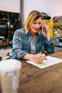 Portrait of happy young woman talking by cellphone in a store.