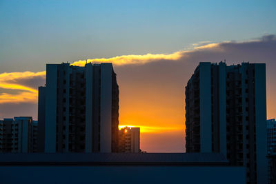 Modern buildings against sky during sunset