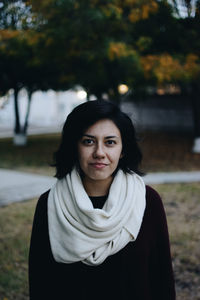 Portrait of young woman wearing scarf standing at park