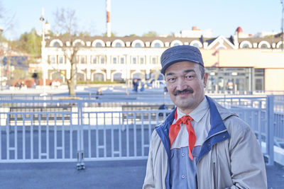Street portrait of senior asian smiling man in red pioneer tie. soviet holiday pioneer day.