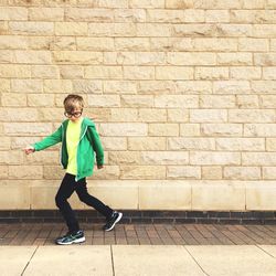 Portrait of young boy standing on sidewalk