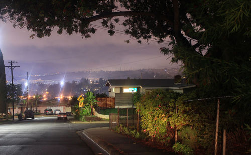 Illuminated city street against sky at night