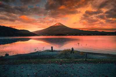 Rear view of men standing by lake against sky