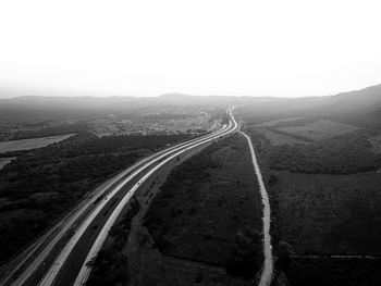 Empty road leading towards mountains against clear sky