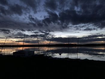 Scenic view of lake against dramatic sky during sunset