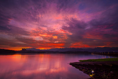 Scenic view of lake against dramatic sky during sunset