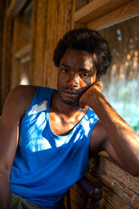 Portrait of young man sitting by window at home