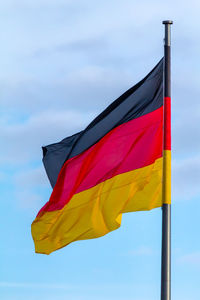 Federal republic of germany, german national flag waving on the blue sky background, de