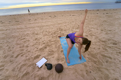 High angle view of woman exercising on sand at beach