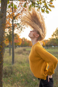 Young woman looking away while standing on tree