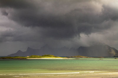 Scenic view of mountains and sea against storm clouds