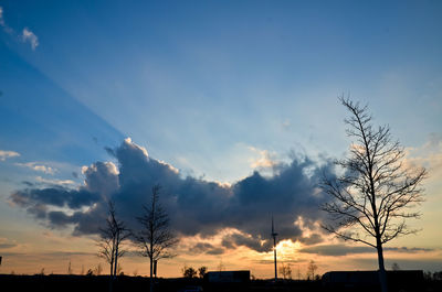 Silhouette of bare trees against sky at sunset