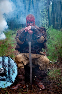 Portrait of man holding camera in forest