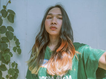 Portrait of young woman standing against wall