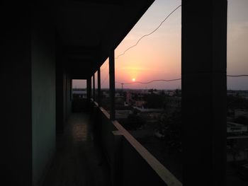 Silhouette buildings against sky during sunset seen through window