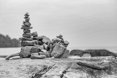 Stack of rocks by sea against clear sky