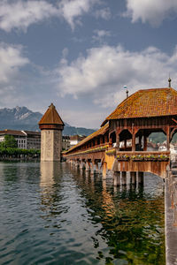 Bridge over lake by buildings against sky