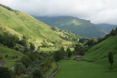 Scenic view of green landscape and mountains against sky