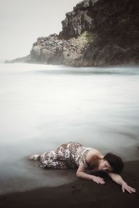 High angle view of woman lying on shore at beach