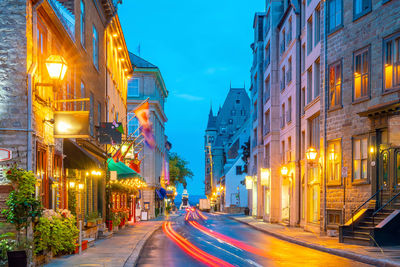 Illuminated light trails on street amidst buildings at night