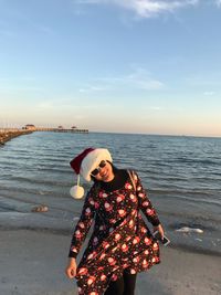 Portrait of woman standing at beach against sky