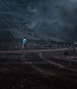 Rear view of man standing on field against sky at night