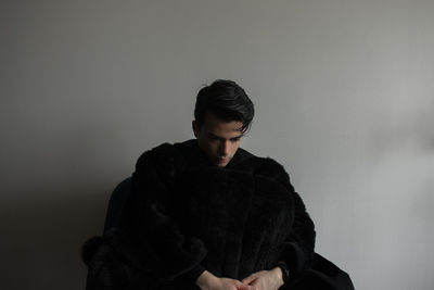 Young man sitting against wall