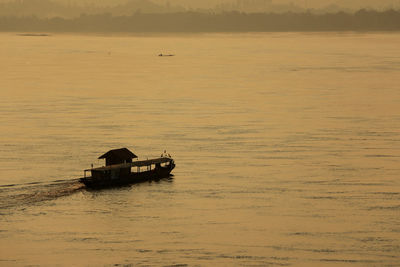 Boat sailing in sea against sky during sunset