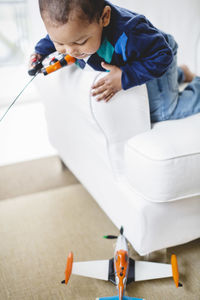 Boy playing with remote controlled airplane at home