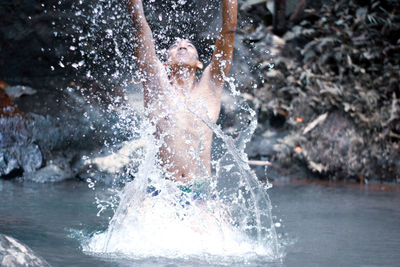 Portrait of woman splashing water in swimming pool