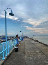 Man on pier by sea against sky