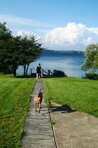 Dog on walkway with woman in background against lake