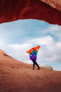 Woman standing on multi colored umbrella against sky