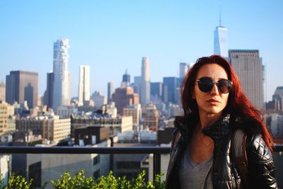 Portrait of beautiful woman in city against clear sky