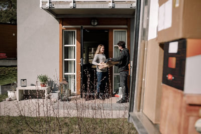 Delivery man delivering package to customer at entrance of house