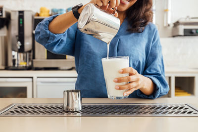 Midsection of woman holding coffee cup at home