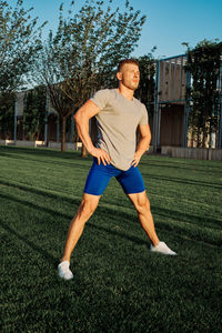 Full length of man sitting on grass against trees