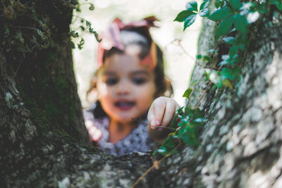 Cute girl picking stick standing by tree trunk