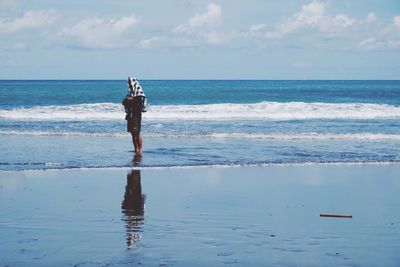 Side view of man at beach against sky