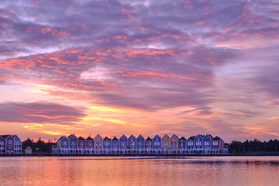 Purple skies and sunset over a lake in houten, netherlands. row of colourful houses in the distance.