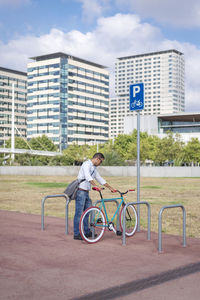 Side view of man bicycling on road against buildings