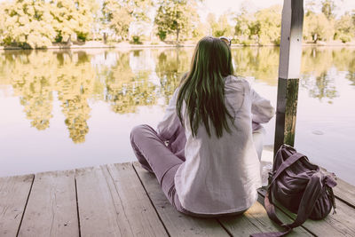 Rear view of woman sitting by lake